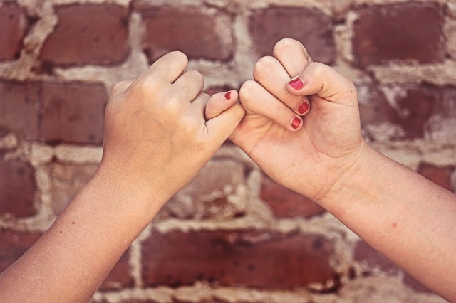 Friend hands pinky swear to keep a promise to pay them back